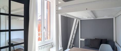 Ein kleines Zimmer mit Etagenbett, Schreibtisch und Stuhl.