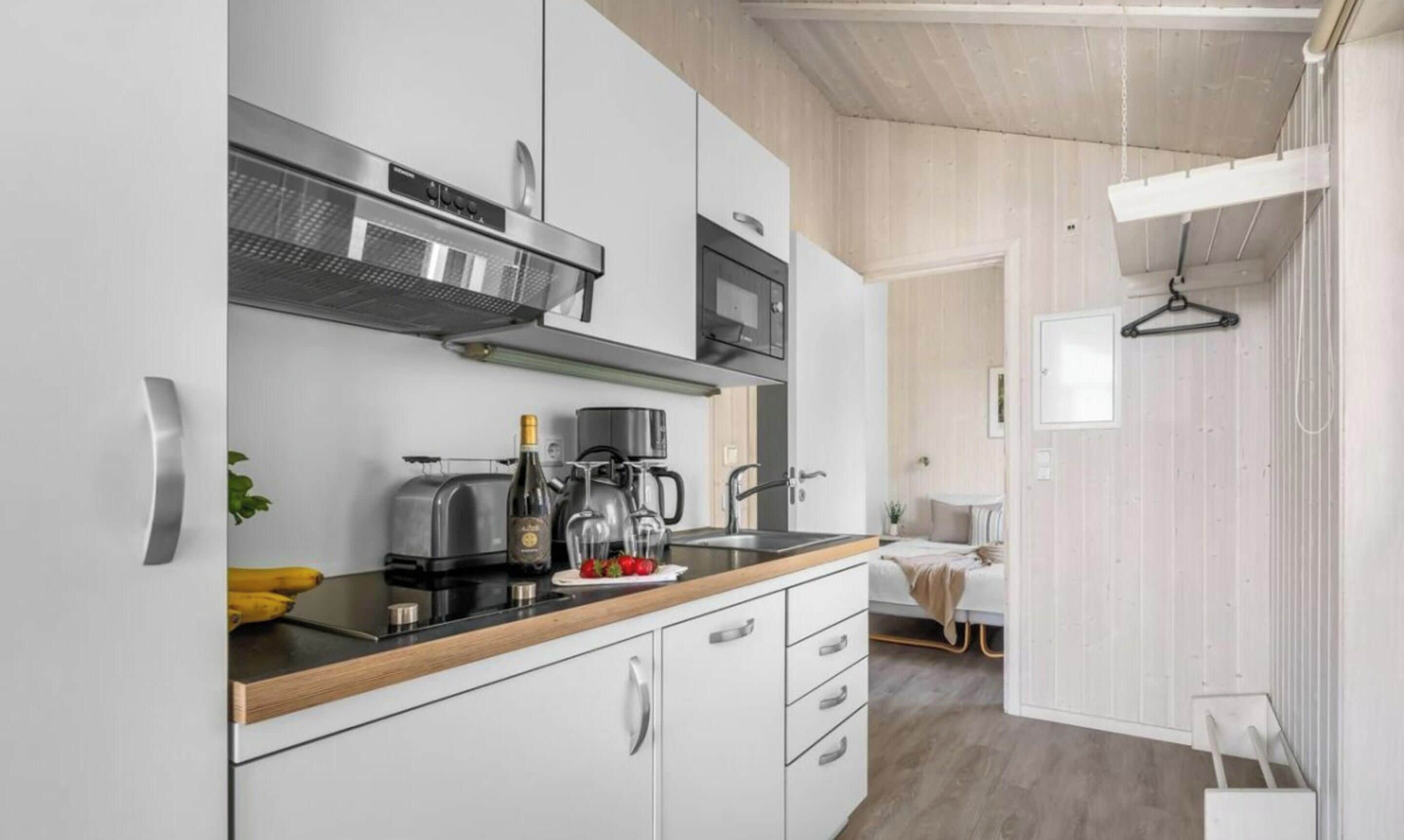 Una cocina moderna con armarios blancos, encimera negra y electrodomésticos de acero inoxidable.