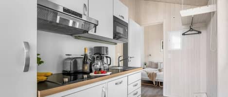 Una cocina moderna con armarios blancos, encimera negra y electrodomésticos de acero inoxidable.