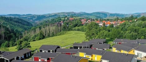 Un quartier résidentiel avec des maisons, un champ verdoyant et des collines en arrière-plan.