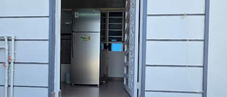 A doorway leading to a kitchen area with a refrigerator and cabinets.