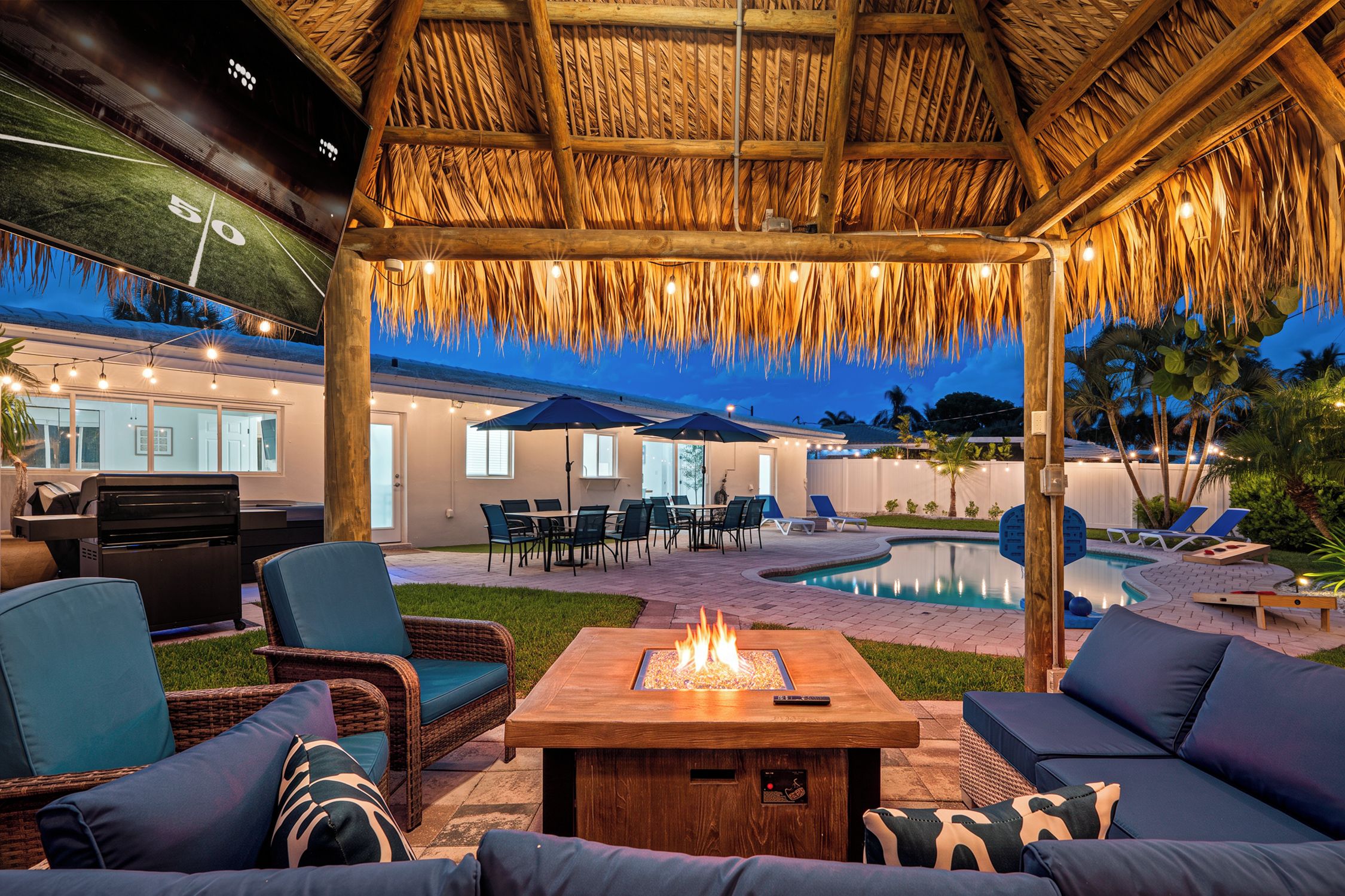 An outdoor patio area with a fire pit, seating, and a pool.