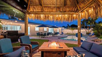 An outdoor patio area with a fire pit, seating, and a pool.