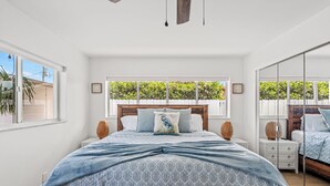 Ein Schlafzimmer mit einem großen Bett, einem Holz-Kopfteil, einem Fenster mit Blick auf Grünflächen und einem Spiegel an der Wand.