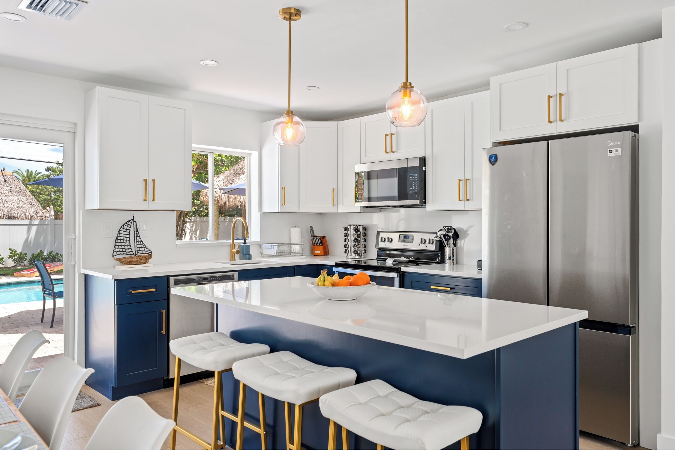 A modern kitchen with white cabinets, a stainless steel refrigerator, and a central island with bar stools.