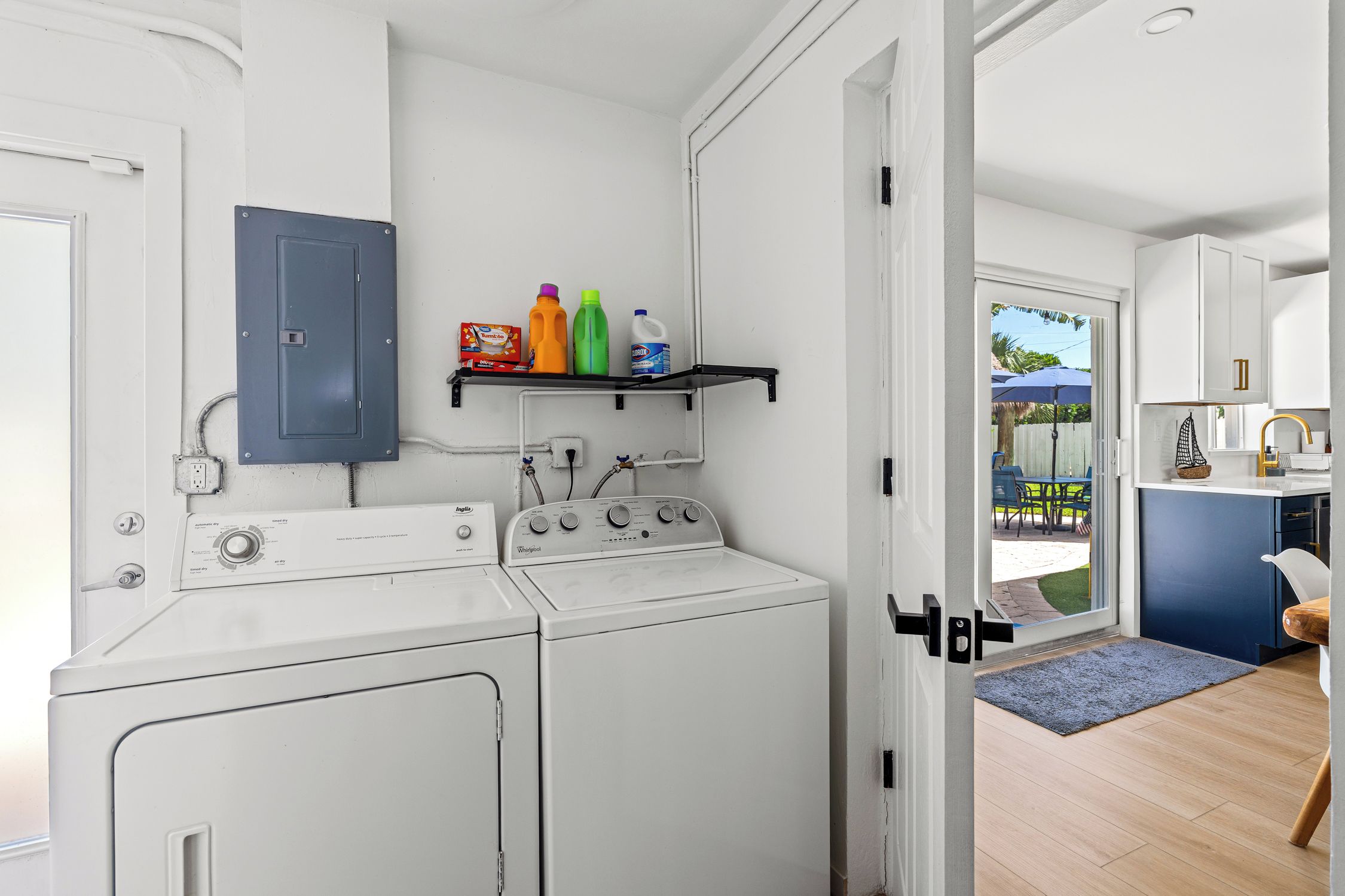 A laundry area with a washing machine, dryer, and a shelf with cleaning products.