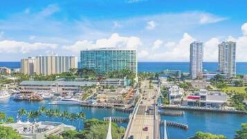A coastal cityscape with a marina, high-rise buildings, and a clear blue sky.