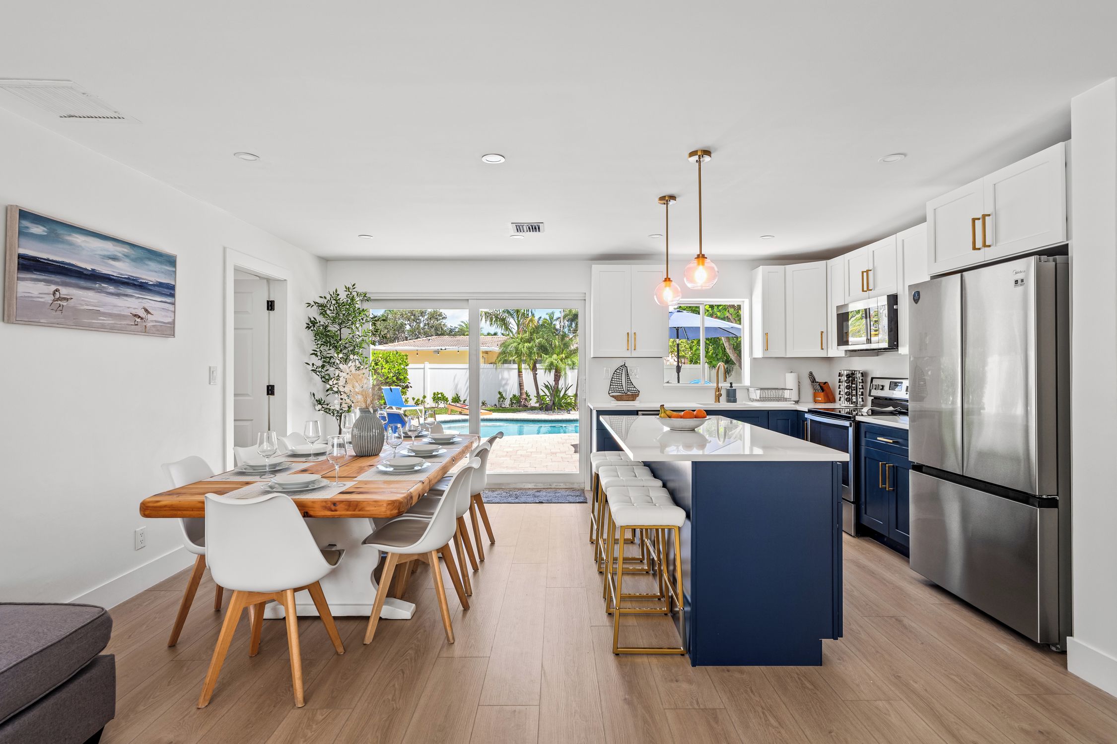 A modern kitchen with a central island, stainless steel appliances, and a dining area with a view of the outdoors.