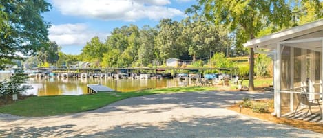A lakeside property with a covered seating area, a dock with boats, and a grassy area.