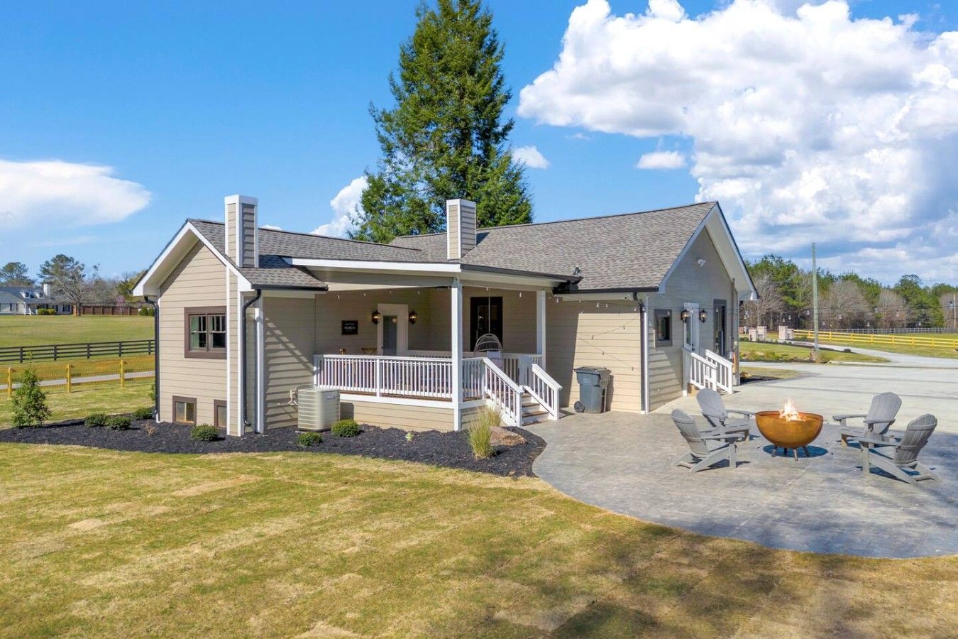 A two-story house with a porch, a fire pit, and a covered patio area.