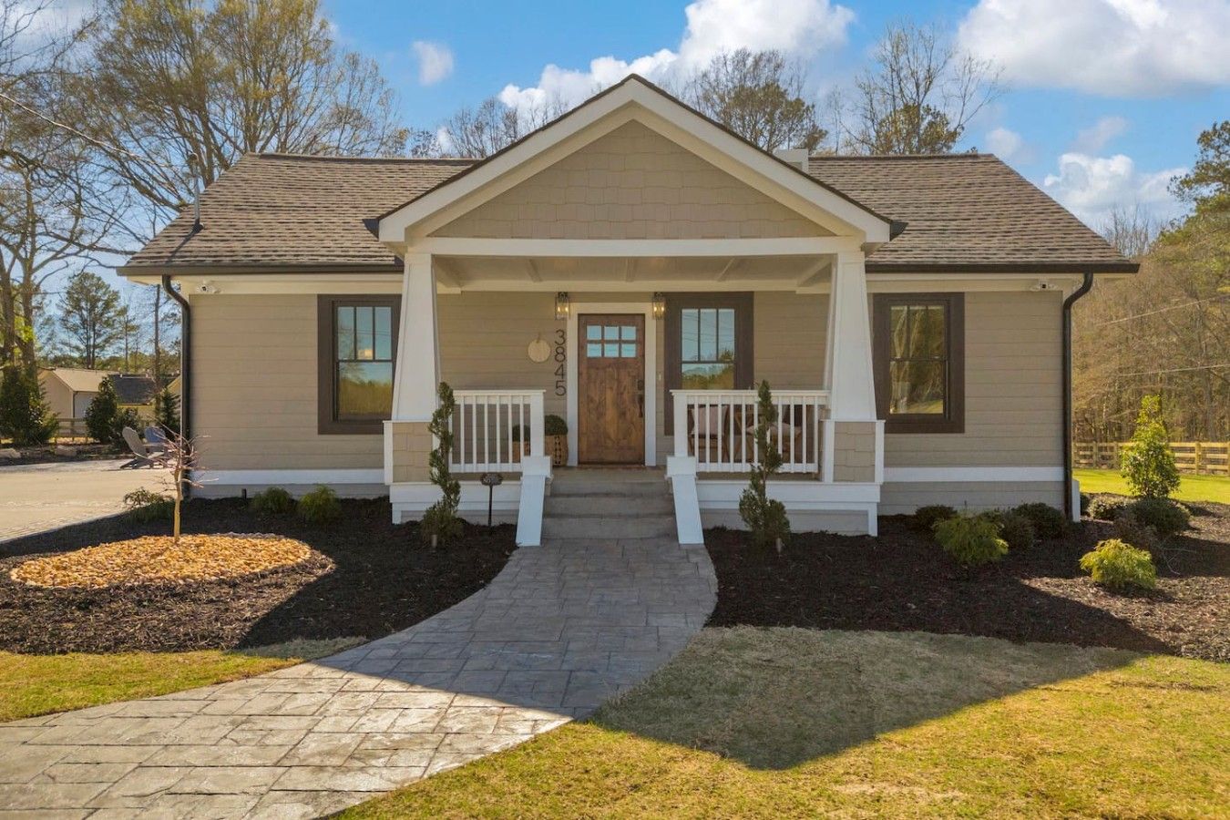 A single-story house with a front porch, a driveway, and a well-maintained lawn.