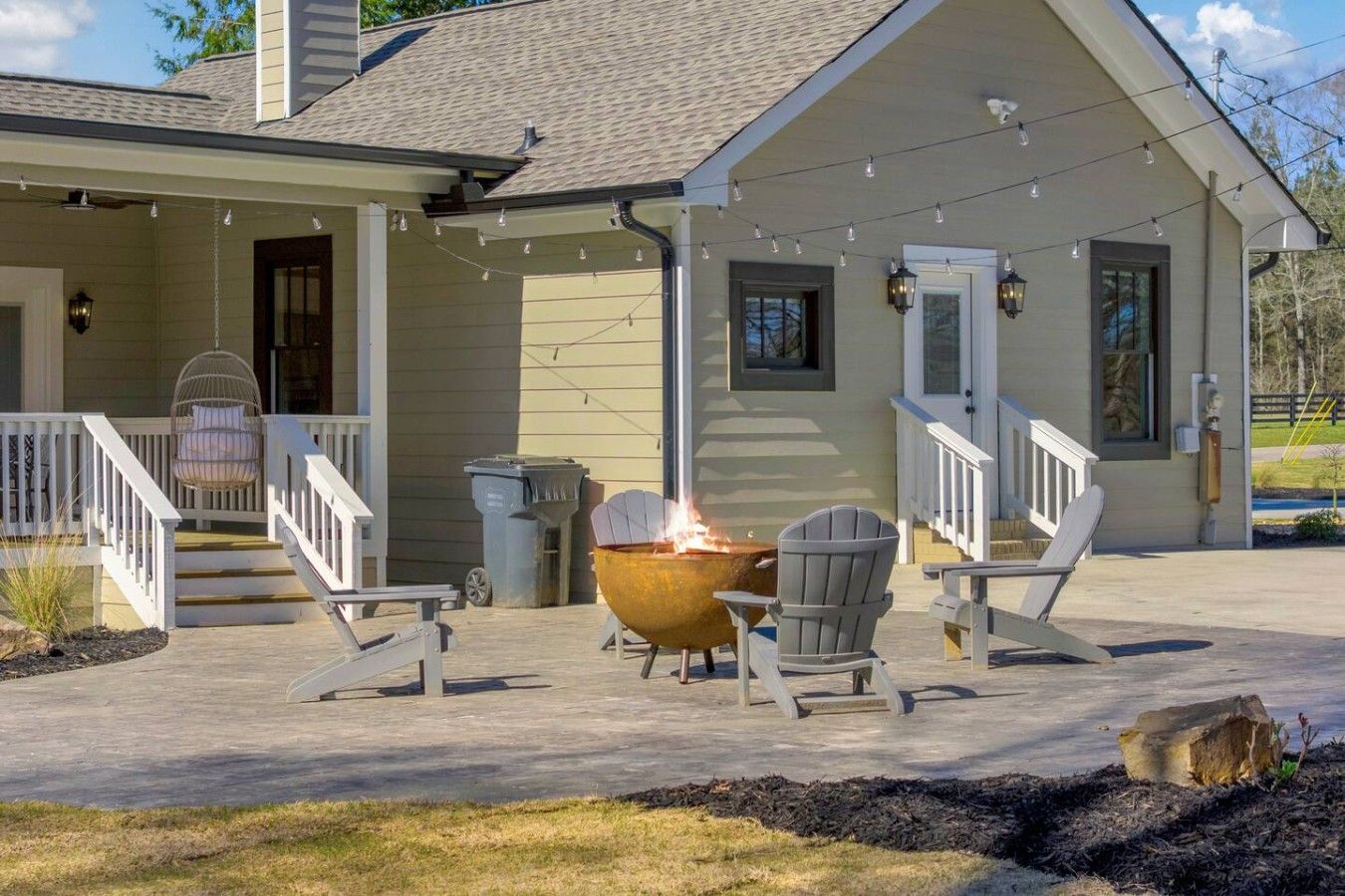 A house with a covered porch, outdoor seating, and a fire pit.