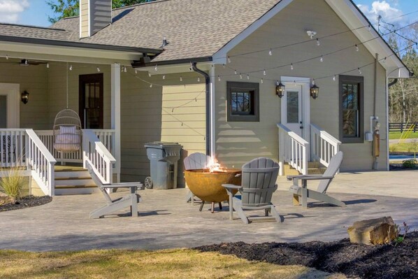 A house with a covered porch, outdoor seating, and a fire pit.
