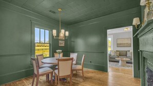 A dining area with a round table and chairs, a chandelier, and a view of a green landscape through a window. - The Eddie At Mount Carmel- Peaceful, Sleeps 4 (Monroe)