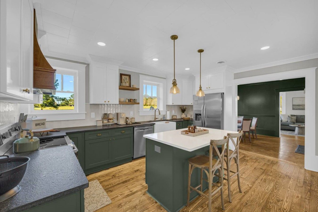 A modern kitchen with a central island, wooden flooring, and pendant lighting.