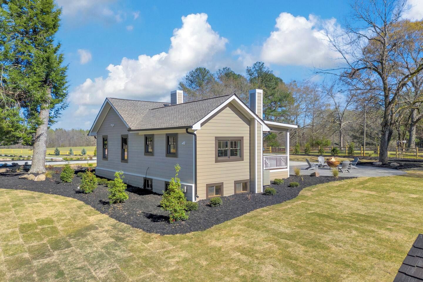 A single-story house with a front porch, surrounded by a well-maintained lawn and a few small trees.