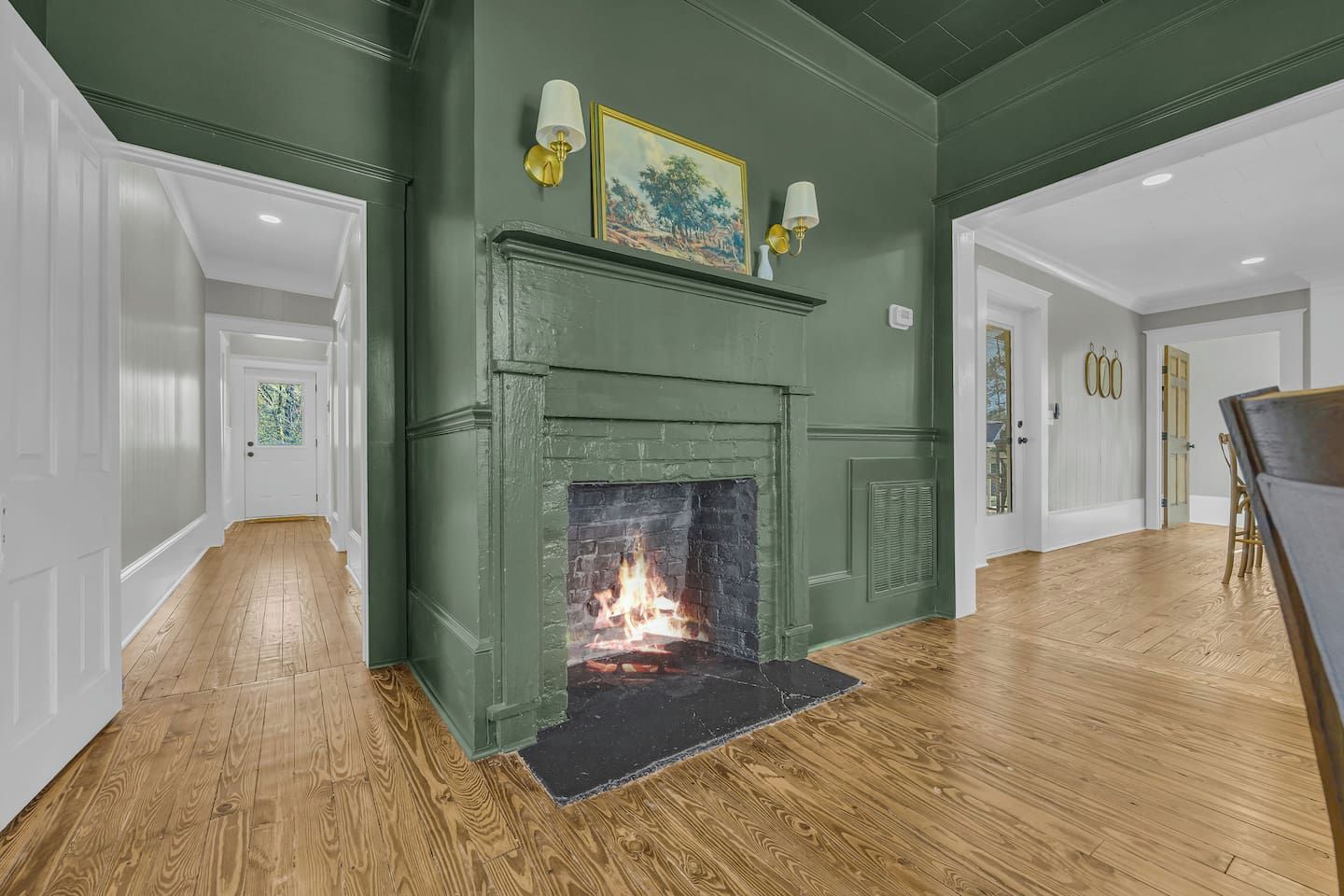 A room with a fireplace, wooden flooring, and a green accent wall.