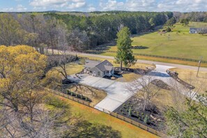 A residential property with a large driveway, a detached garage, and a fenced yard.
