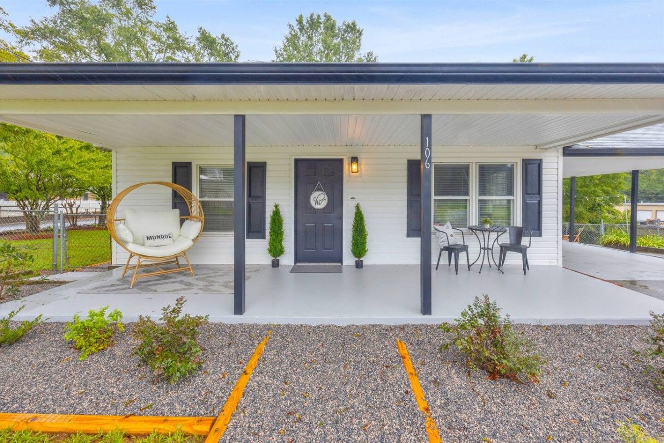 Ein modernes Haus mit überdachter Veranda, einer Schaukel und einer kleinen Terrasse.