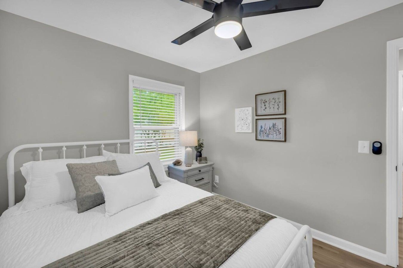 Un dormitorio con cama, mesita de noche, lámpara de pared y ventilador de techo.
