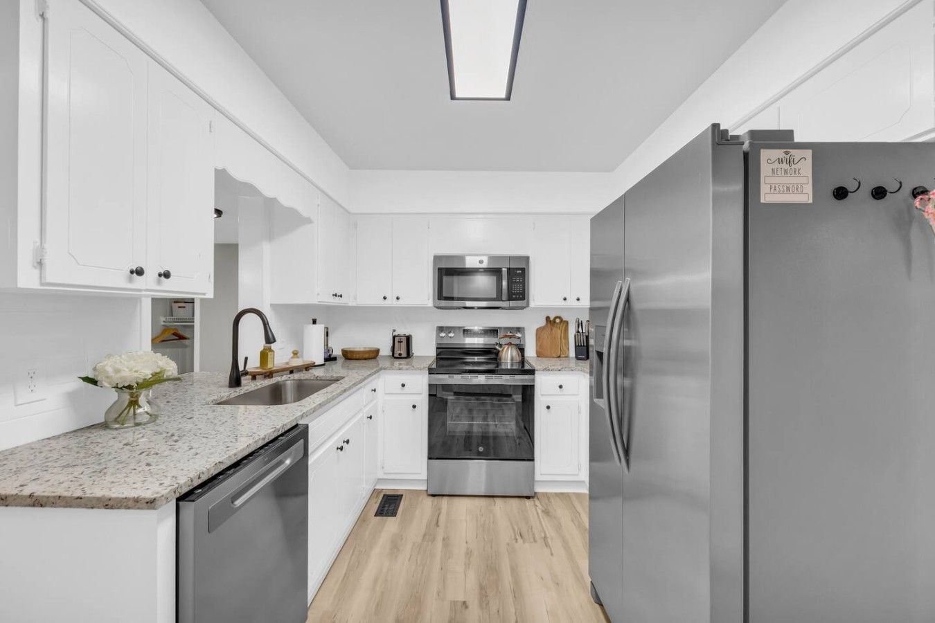 A modern kitchen with white cabinetry, stainless steel appliances, and a granite countertop.
