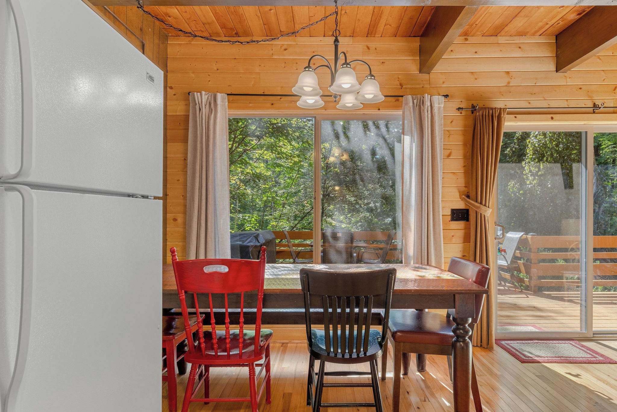 Un intérieur en bois comprenant un coin repas, un réfrigérateur et une vue par la fenêtre.