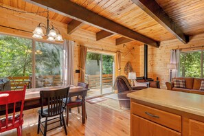 A wooden cabin interior with a dining area, a sofa, and a kitchen counter.