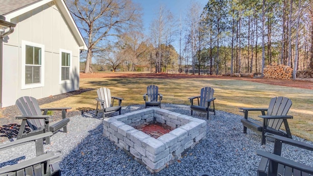 A patio with Adirondack chairs, a stone fire pit, and a house with windows. - The Retreat at Mount Carmel-Peaceful Sleeps 6 (Monroe)