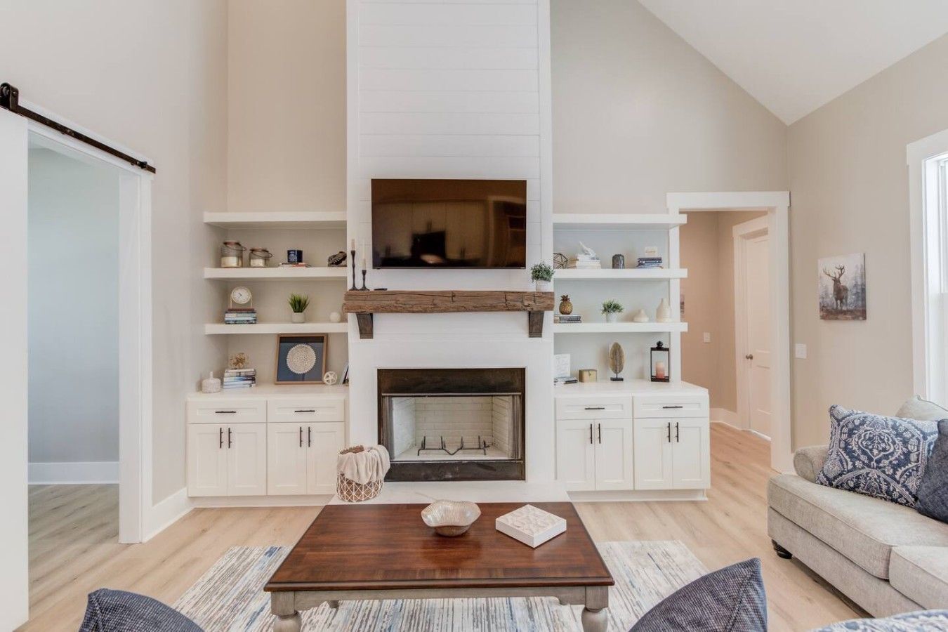 A living room with a fireplace, white cabinetry, a coffee table, and a sofa.