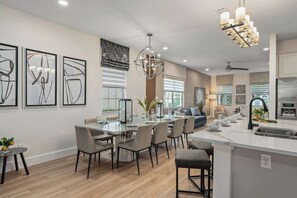 A modern kitchen with a central island, dining area with chairs, and a chandelier. - 4BR Near Disney - Private Heated Pool & Spa (Kissimmee)