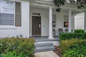 A white building with a brown door, white columns, and a number '7416' above the door. - 4BR Near Disney - Private Heated Pool & Spa (Kissimmee)