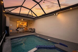 An indoor swimming pool with a glass ceiling, a seating area with chairs and a table, and a view of the sky. - 4BR Near Disney - Private Heated Pool & Spa (Kissimmee)