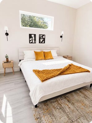 Ein Schlafzimmer mit einem Bett, zwei Nachttischen, einer Fensterbank und Wandlampen.