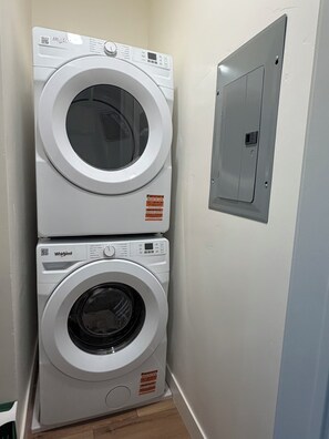 Zwei übereinander gestapelte Whirlpool Waschmaschinen in einem Waschraum mit grauer Elektroleiste an der Wand.