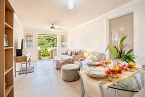 A spacious living area with a dining table set for a meal, a sofa, and a television. - Barbados dream home - the perfect place to stay (Oistins)