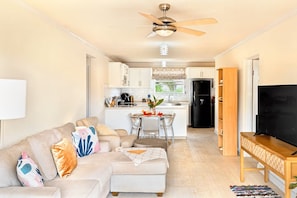 A living room with a sofa, a TV stand, and a dining area with a table and chairs. - Barbados dream home - the perfect place to stay (Oistins)