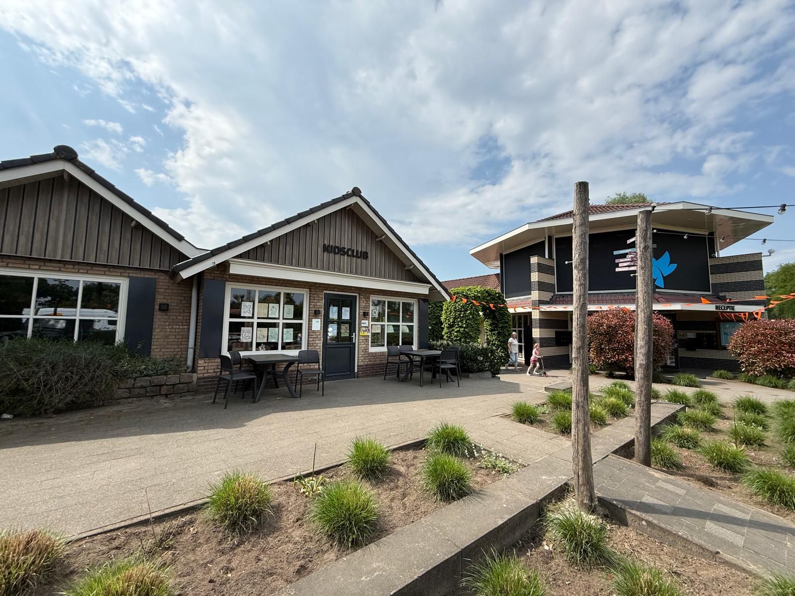 A building with a 'KIDS CLUB' sign, outdoor seating, and a reception area.