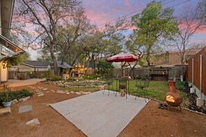 A backyard with a patio, outdoor seating, a fire pit, and a decorative fence. - Spacious 4-bedroom house near Art house and 150 acre Preserve (Austin)