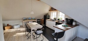 A kitchen with a dining area, wooden flooring, and a sloped ceiling. - Gleenbach Vacation Home with a Balcony (Kirtorf)