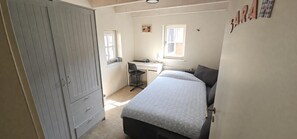 Ein Schlafzimmer mit einem Bett, einem Schreibtisch und einem Kleiderschrank.