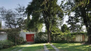 Zona residencial con una puerta roja, un camino pavimentado y un árbol en primer plano.