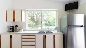 Cocina moderna con refrigerador de acero inoxidable, pileta doble y ventana con vista a follaje.