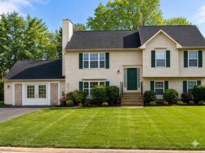 A two-story house with a front entrance, a garage, and a well-maintained lawn. - Cozy 1-bedroom studio in soothing Fredericksburg (Fredericksburg)