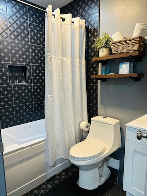 Un baño con bañera, inodoro y cortina de ducha.