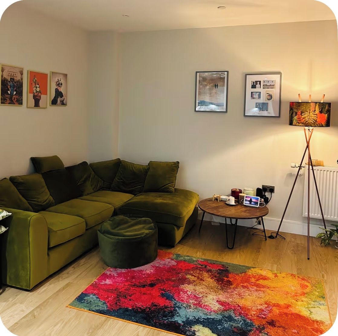 Ein Wohnzimmer mit einem Ecksofa, einem kleinen Couchtisch und einem farbenfrohen Teppich.