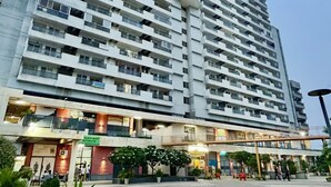 Un edificio alto con numerosi balconi e una zona commerciale a livello strada.
