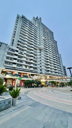 Un edificio de gran altura con múltiples balcones y un área comercial en la planta baja.