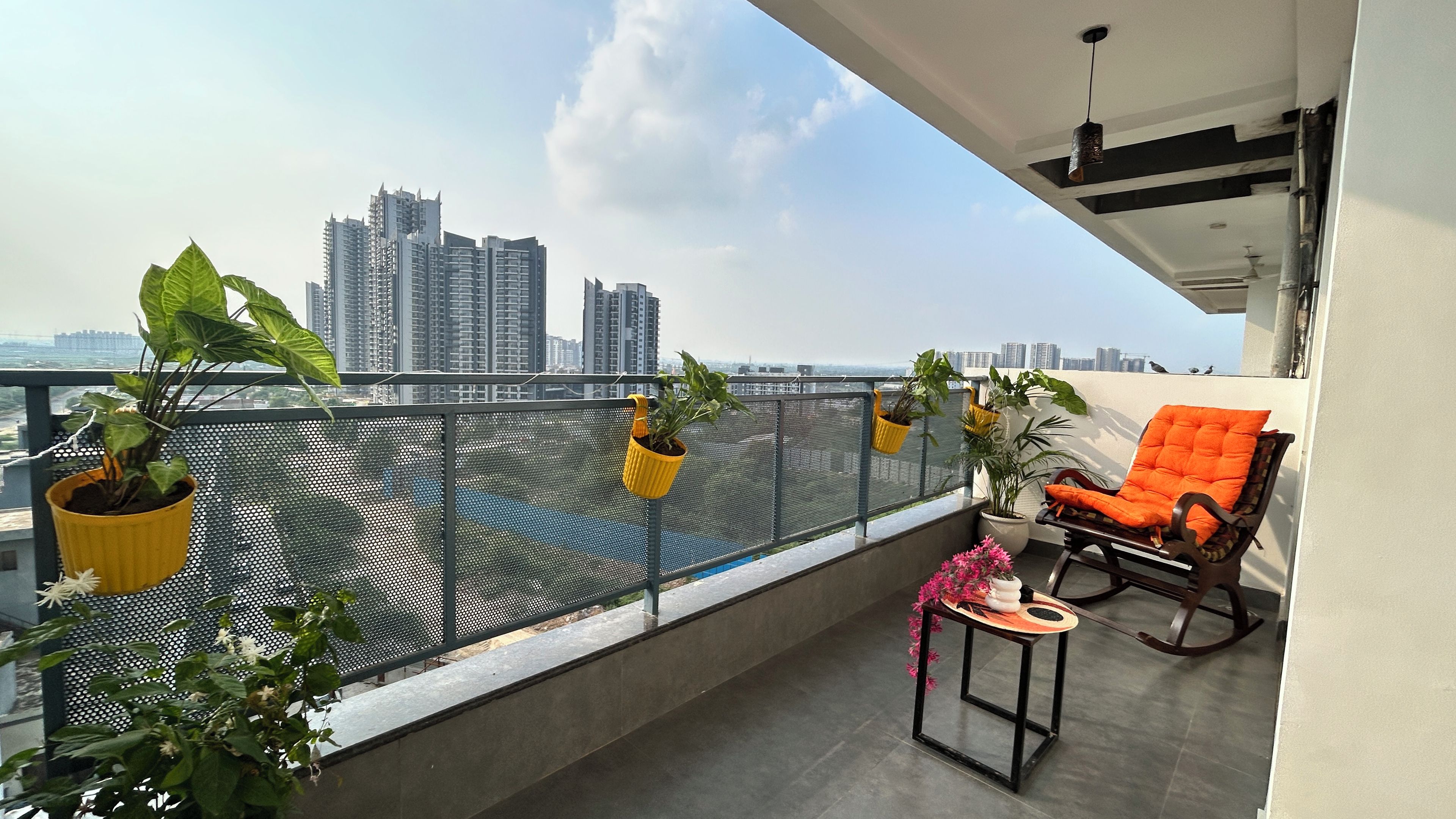 A balcony with a city view, potted plants, and a seating area.