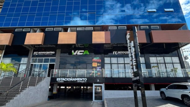 En modern byggnad med en glasfasad, flera kommersiella lokaler, inklusive ett Novocentro och ett VCA, samt en tydlig entré med en ramp.