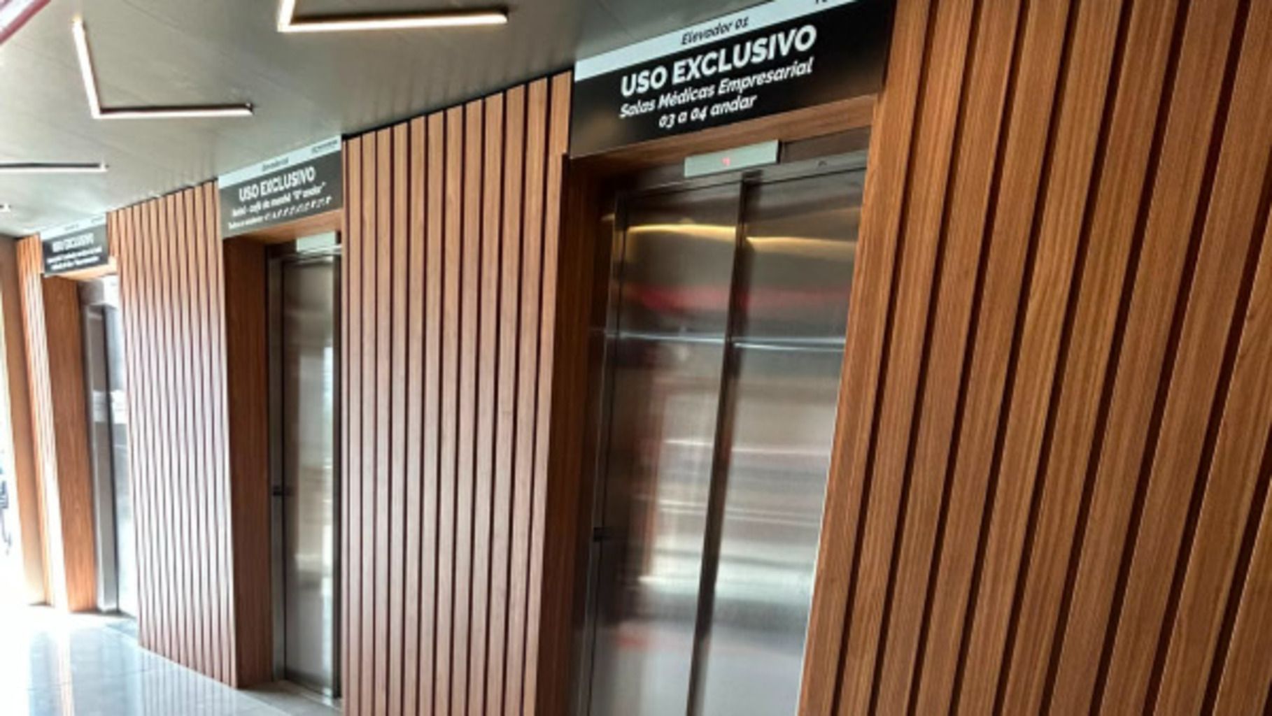A modern building with vertical wooden paneling and a sign indicating an exclusive use elevator.
